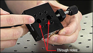The oversized through holes in the top plate of a translation stage are used to access the mounting points in the base plate.